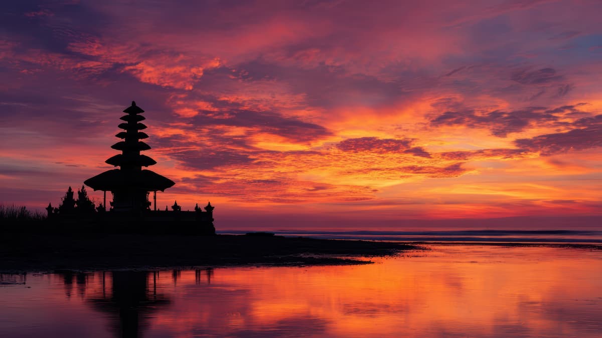 bali sunset with balinese temple sat next to the water
